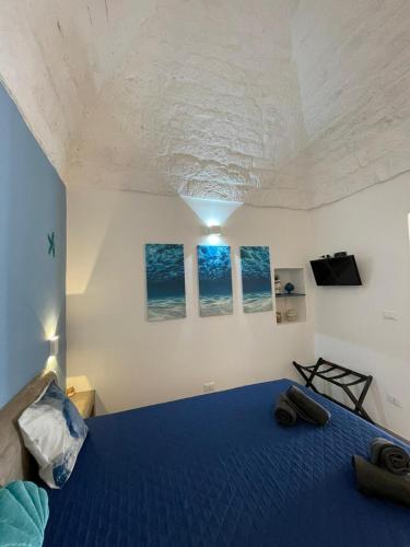 ein Schlafzimmer mit einem blauen Bett mit drei Bildern an der Wand in der Unterkunft L'Ostrica in Ostuni