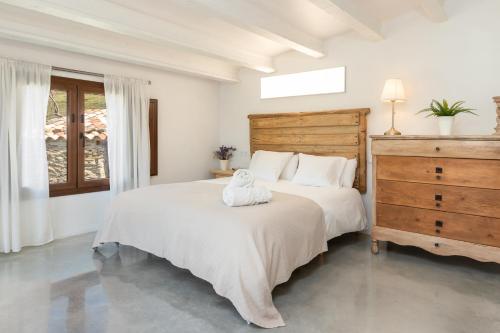 a white bedroom with a large bed and a dresser at El Roure in Molló