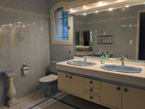 une salle de bain avec deux lavabos et un WC et un miroir dans l'établissement Magnifique villa vue mer avec jacuzzi, à La Turbie
