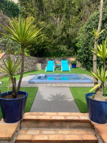 une piscine avec deux chaises bleues et deux palmiers dans l'établissement Magnifique villa vue mer avec jacuzzi, à La Turbie