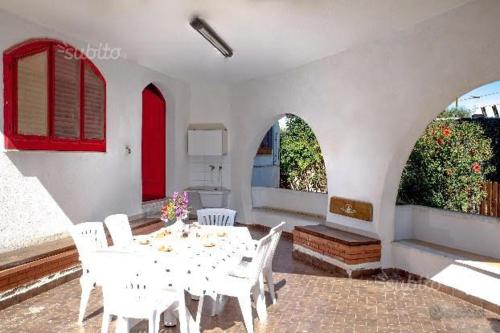 Camera bianca con tavolo, sedie e finestre di La Rosa dei Venti a Licata