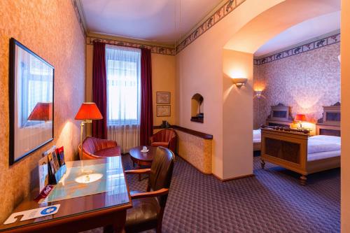 a hotel room with a bedroom with a desk and a bed at Hotel Continental in Plzeň