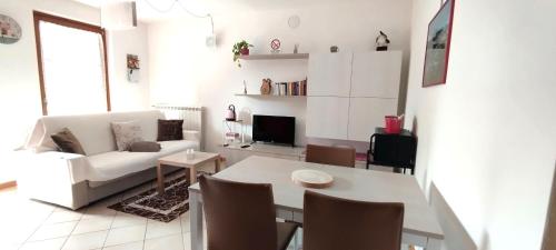 a living room with a white couch and a table at Casa Vacanza IL CICLAMINO in Borno