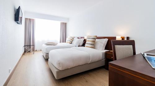 a hotel room with two beds and a couch at Albergaria Quim Barreiros in Vila Praia de Âncora