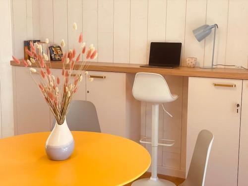 une table jaune avec un vase avec des fleurs sur elle dans l'établissement Esprit Cabane La Hume - Terrasse & Vue sur le Port, à Gujan-Mestras