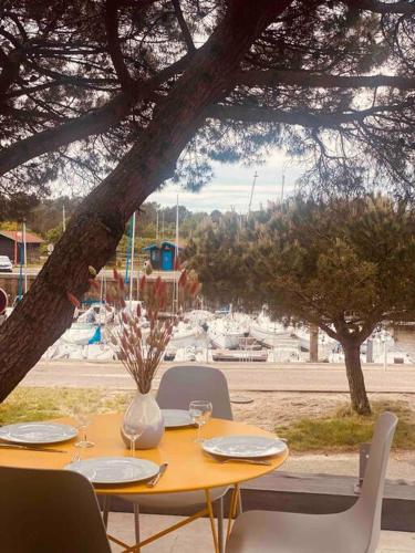 une table avec des chaises et un vase de fleurs dessus dans l'établissement Esprit Cabane La Hume - Terrasse & Vue sur le Port, à Gujan-Mestras