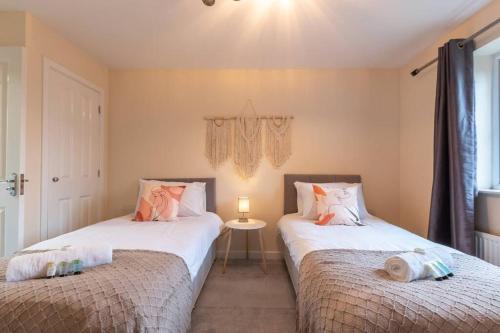 duas camas sentadas uma ao lado da outra num quarto em 3-Bedroom Home in Peterborough with Free Parking & Netflix by HP Accommodation em Peterborough
