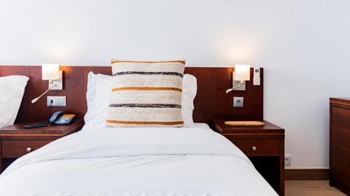 a bedroom with a bed with two night stands and two lamps at Albergaria Quim Barreiros in Vila Praia de Âncora