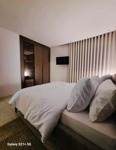 a bedroom with a bed with white sheets and pillows at Une véritable perle rare in Sfax