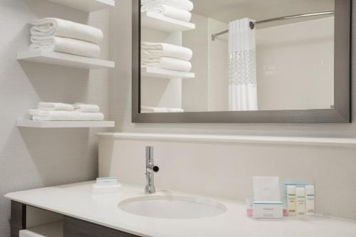 een badkamer met een wastafel, een spiegel en handdoeken bij Hampton Inn & Suites West Des Moines Mill Civic in West Des Moines