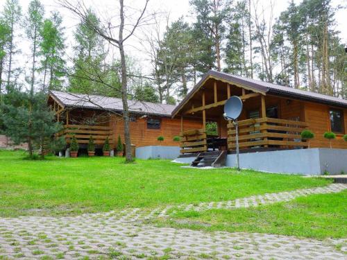 a log cabin with a porch and a grassy yard at DOMKI , Pokoje gościnne Ustronie in Zwierzyniec