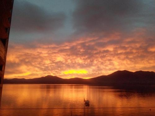 a sunset over a lake with a boat in the water at Trattoria Della Cascata B&B in Oggebbio