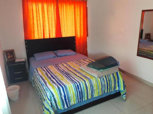 a bedroom with a bed with a colorful blanket and a window at Casa 4 in Medellín