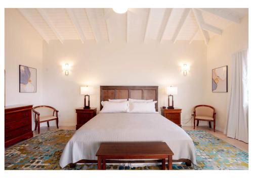 1 Schlafzimmer mit einem großen Bett und 2 Stühlen in der Unterkunft Oasis with Pool Hot Tub & Sauna in Rodney Bay Village