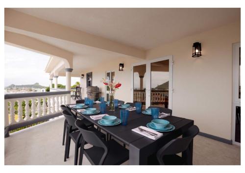 une table avec des assiettes bleues et des chaises sur un balcon dans l'établissement Luxurious Oasis for groups, à Rodney Bay Village