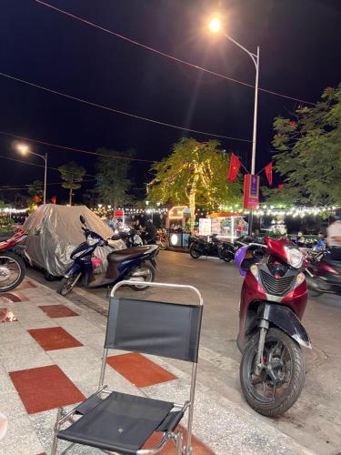 a chair and a motorcycle parked on a street at night at Ez mart and stay in Hai Phong