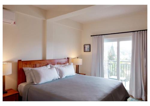 ein Schlafzimmer mit einem Bett mit weißen Kissen und einem Fenster in der Unterkunft Sauna Pool Game Room Bliss in Rodney Bay Village
