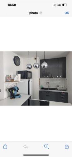 une cuisine avec des armoires noires et un comptoir blanc dans l'établissement Appartement mer, à La Grande Motte