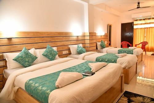 three beds in a room with green and white at Hotel Sea Rock Porte Blair in Port Blair