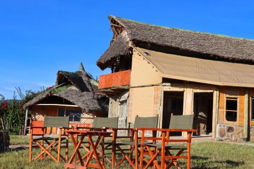 a house with chairs and a table in front of it at Orng'atuny Mara King Camp in Masai Mara