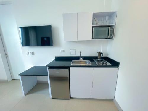 eine weiße Küche mit einer Spüle und einer Mikrowelle in der Unterkunft Apartaestudio Brumilo 3 in Montería
