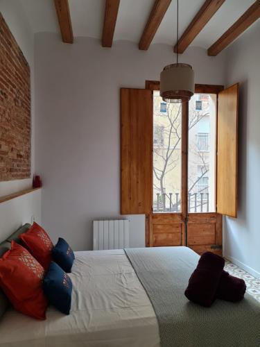 バルセロナにあるPoble Sec Charming Apartmentのベッドルーム1室(赤と青の枕が備わるベッド1台付)