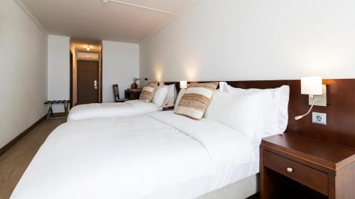 a bedroom with two white beds and a wooden headboard at Albergaria Quim Barreiros in Vila Praia de Âncora