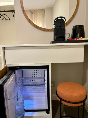 a small refrigerator with a stool and a mirror at Camere di Bianca in Foligno