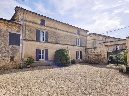 an old stone building with a driveway in front of it at La spacieuse maison des miots in Hiersac