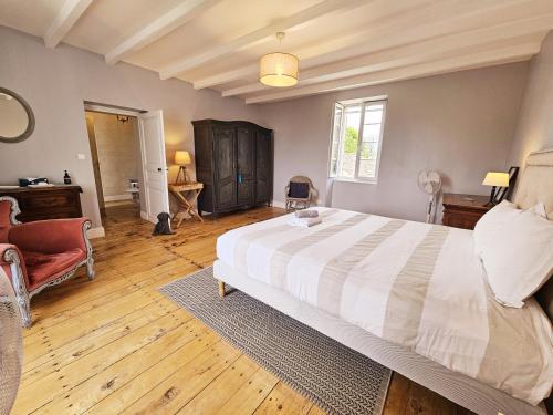 a bedroom with a large white bed and a chair at La spacieuse maison des miots in Hiersac