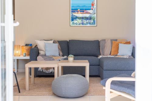 ein Wohnzimmer mit einem blauen Sofa und einem Tisch in der Unterkunft Maison Cap Brun Jardin Parking in Toulon