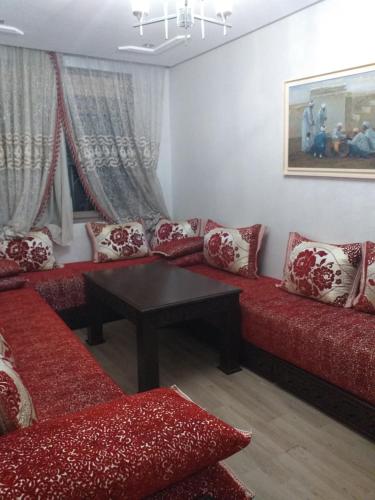 una sala de estar con sofás rojos y una mesa. en الدار البيضاء بوركون, en Aïn Harrouda