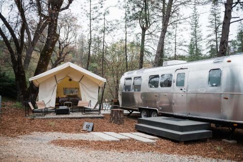 a tent and a trailer parked in the woods at AutoCamp Sequoia in Three Rivers