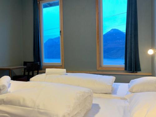 three beds in a room with two large windows at Winjum Hostel Stegastein in Aurland