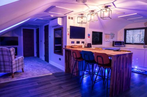 a kitchen with a large wooden bar with stools at Chestnut retreat a stunning Annex apartment in Ossett