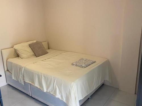 a small bed in a small room with a white sheet at Green Flash Apartments in Lance aux Épines