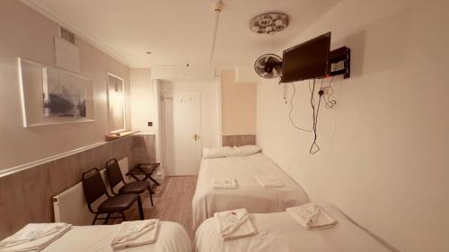 a small room with two beds and two chairs at Earls Court Hotel in London