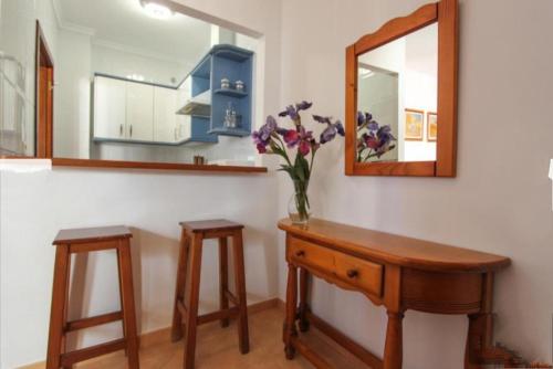 Un jarrón de flores sobre una mesa con un espejo. en AyD, en Nerja