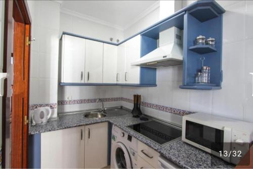 Una cocina con gabinetes azules y blancos y un fregadero. en AyD, en Nerja