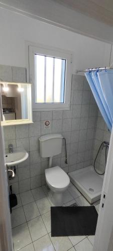 a bathroom with a toilet and a sink and a window at KANALI HOLIDAYS APARTMENT 3 in Kanali