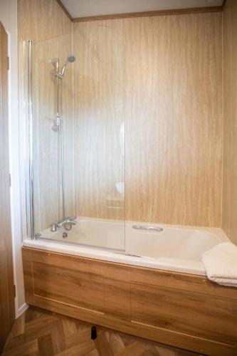 a bathroom with a bath tub with a shower at Stewarts Resort Lodge 16 in St. Andrews