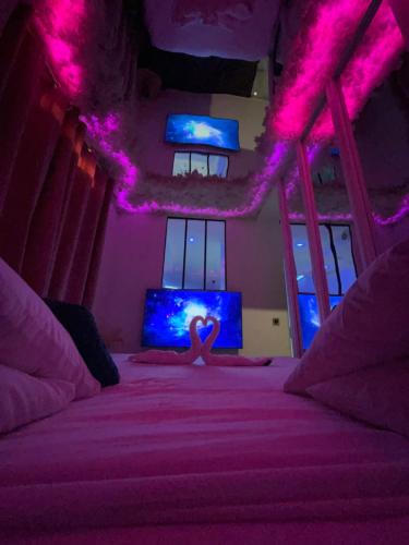 Un dormitorio con una cama con luces moradas. en Le BLUE, en Aubervilliers