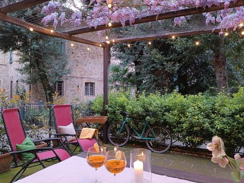 une table et des chaises sous une pergola avec des fleurs violettes dans l'établissement Casa con Giardino Pieno Centro Storico a Due Passi dal Duomo, à Orvieto