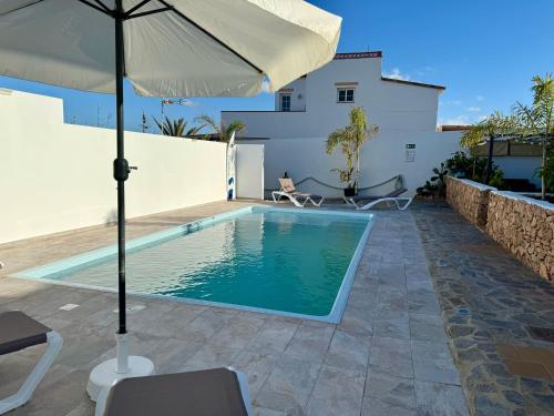 einen Pool mit Sonnenschirm neben einem Haus in der Unterkunft Villa Residencial El Guaidil in Triquivijate
