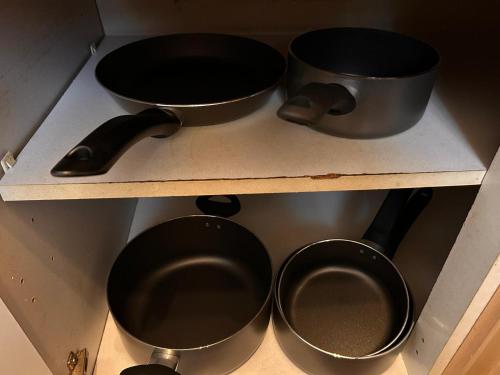 four pots and pans on a shelf in a kitchen at Stunning one bed Apartment with free Wifi and Parking in Goodmayes