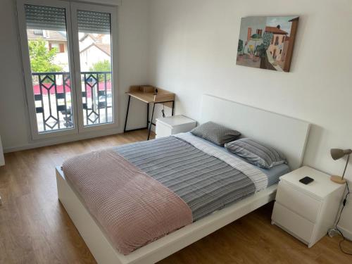 une chambre blanche avec un lit et un balcon dans l'établissement Appartement Cosy proche PARIS CDG parking, au Blanc-Mesnil