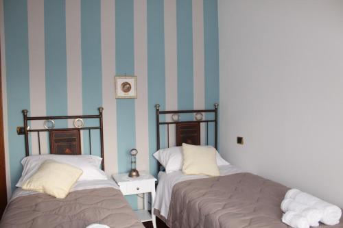 twee bedden in een kamer met blauwe en witte strepen bij Sosta in Sila in Spezzano Piccolo