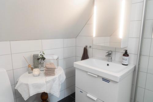 a white bathroom with a sink and a mirror at Duveslätt B & B in Åskloster