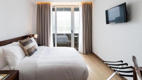 a hotel room with a bed and a television at Albergaria Quim Barreiros in Vila Praia de Âncora