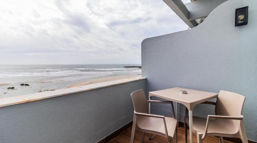 a table and chairs on a balcony with a view of the beach at Albergaria Quim Barreiros in Vila Praia de Âncora
